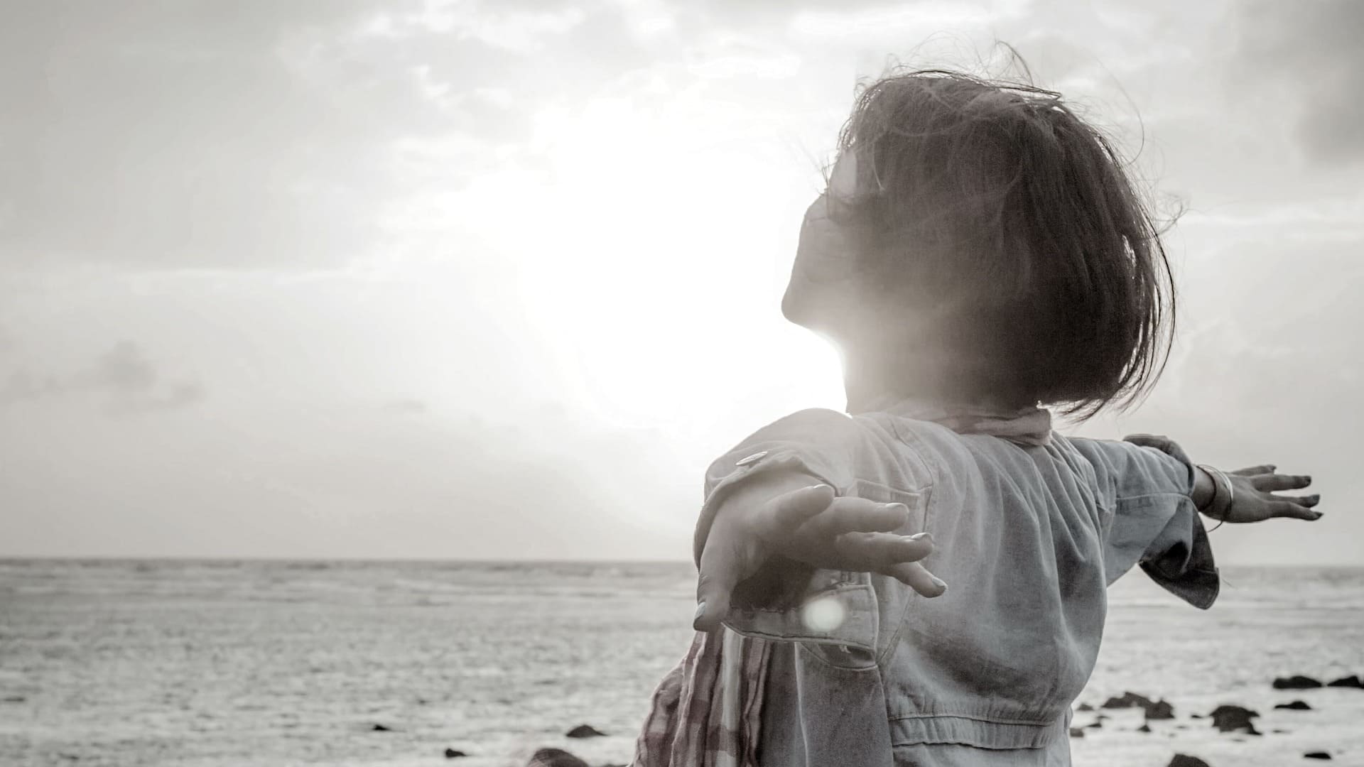 Person standing with arms outstretched, symbolizing hope, healing, and freedom for survivors of human trafficking.